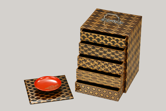 A set of tiered boxes with a handle with pine, bamboo and plum design in makie