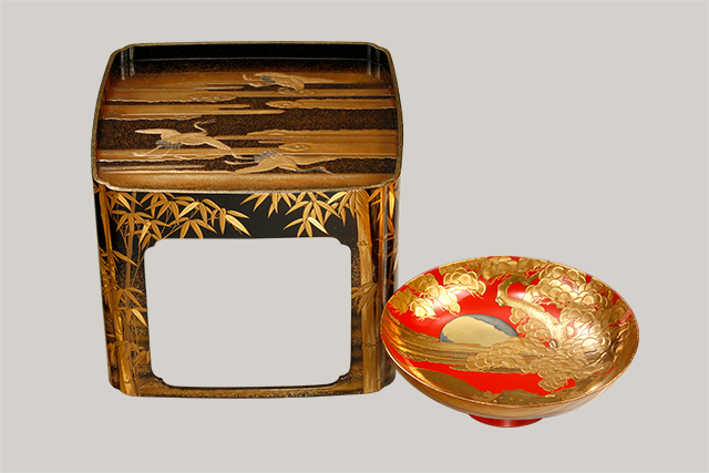 A set of large sake cup with pine, bamboo, plum and crane design in makie and a stand